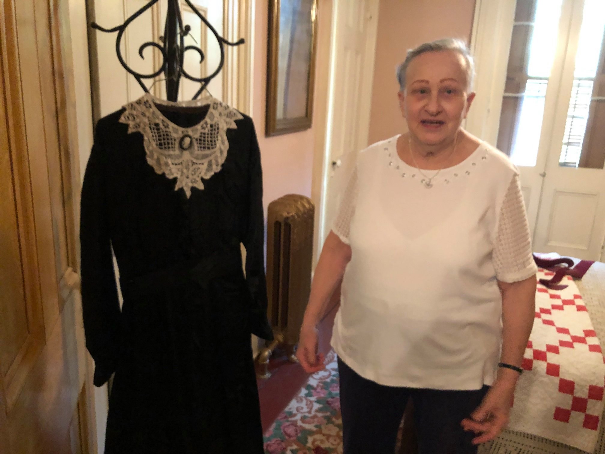 Photo: Docent Kaye Hubbard with her great-grandmother’s dress, now on display in the Downstairs Bedroom